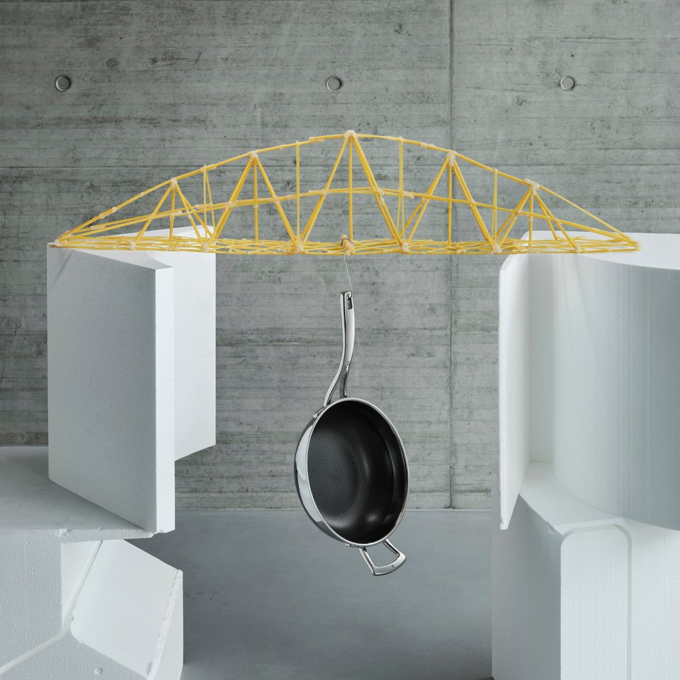 Darstellung einer Brücke aus Spaghetti, an der eine Pfanne hängt
