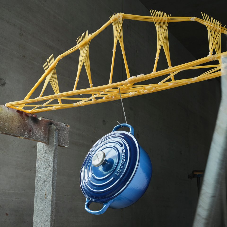 Darstellung einer Brücke aus Spaghetti, an der ein Topf hängt
