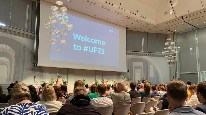 Konferenzteilnehmerinnen und -teilnehmer sitzen im Veranstaltungssaal.