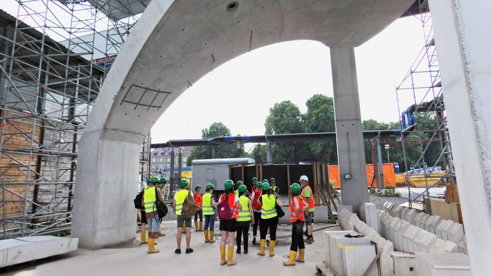 UmLog Studierende stehen unter einer Probesäule auf der Baustelle von Stuttgart 21